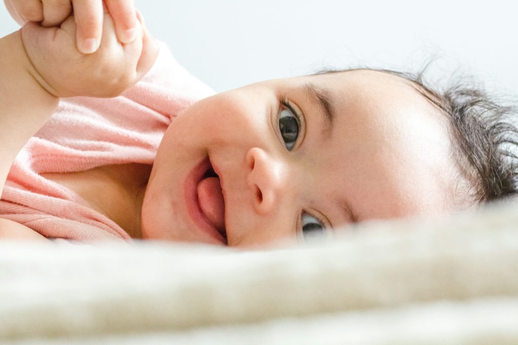 smiling baby lying on its side facing camera